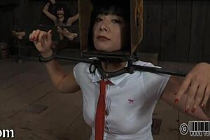 Woman performs emotional striptease inside cage, clothes ripped