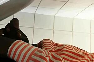 Black gay guy at public urinal stroking cock while spying.