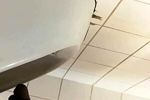 Black gay guy at public urinal stroking cock while spying.