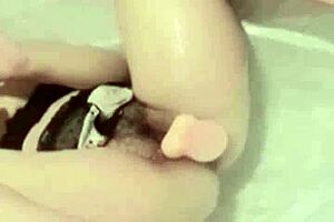 This Asian girl is masturbating in the bathroom with a dildo while watching porn.