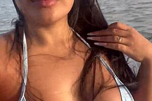 Latina woman in bikini sunbathes on the deck of a boat with her husband