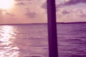 Latina woman in bikini sunbathes on the deck of a boat with her husband