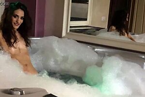 This pretty skinny teen is bathing in the tub, chatting online while touching herself