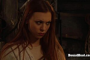 The busty lesbian slave moans loudly while her mistress fingers her wet pussy in bondage.